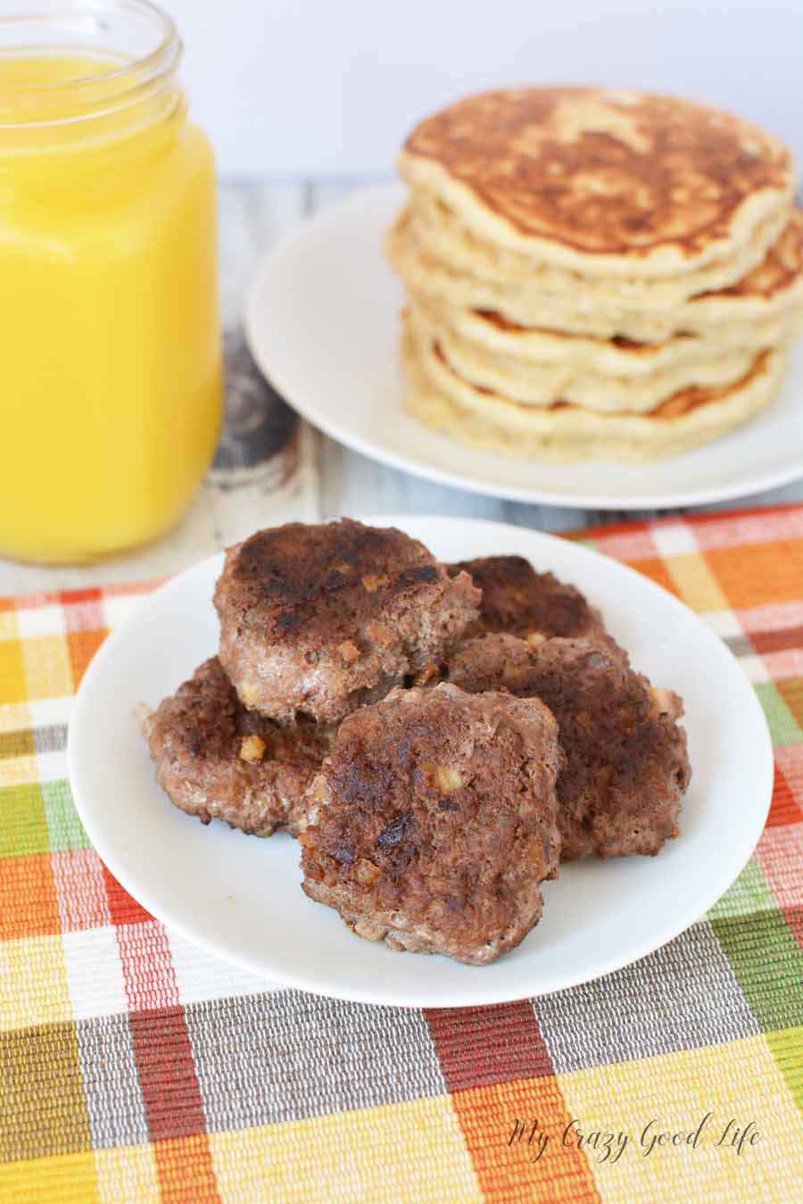 Finished sweet homemade sausage on a plate with some delicious pancakes and orange juice to go with it! 