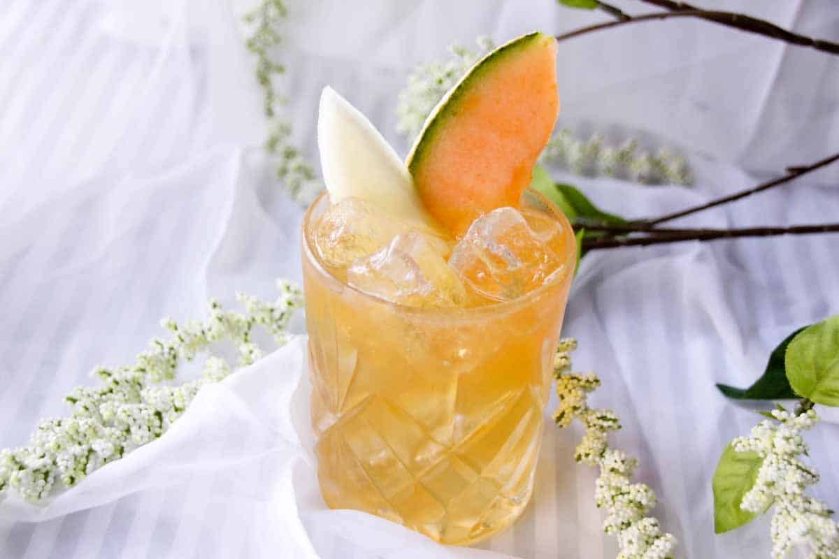 Clear glass with rum margarita inside, garnished with papaya slices.