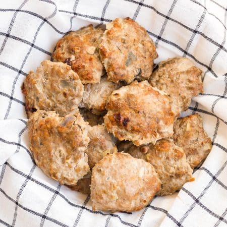 A white and black striped napkin lining a bowl and filled with homemade turkey sausage patties.