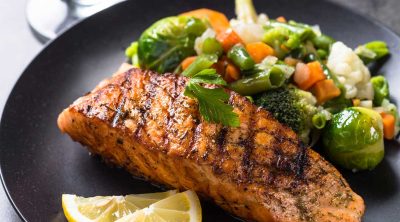 perfect 2b mindset dinner - on a black plate, grilled salmon with 1/2 the plate of veggies