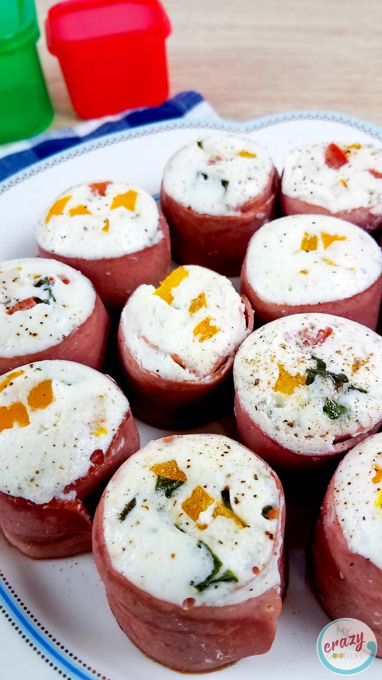egg white bites on a white plate- wrapped in turkey bacon