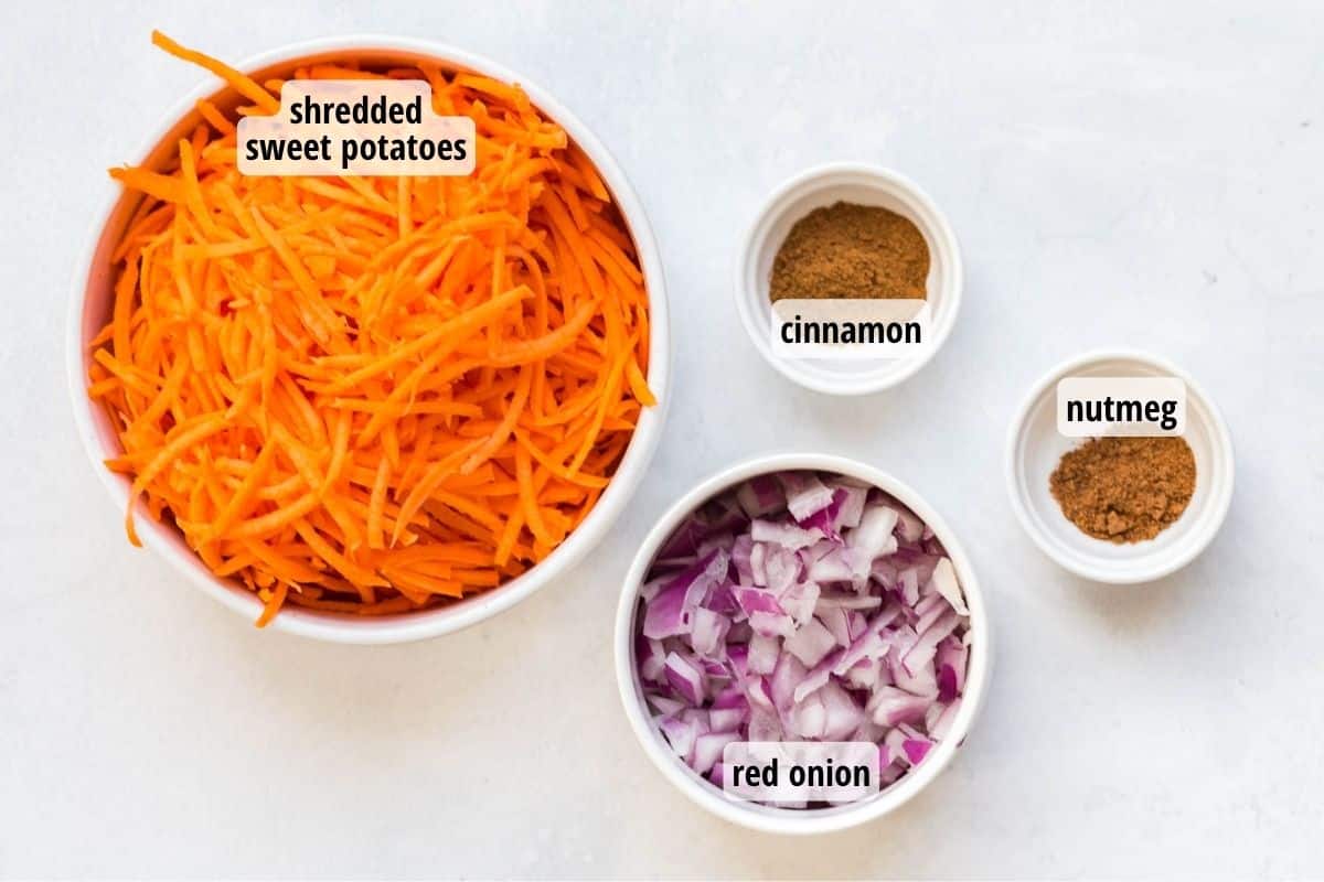 Four bowls on a white counter top with labeled ingredients such as shredded sweet potato, red onion, cinnamon, and nutmeg.