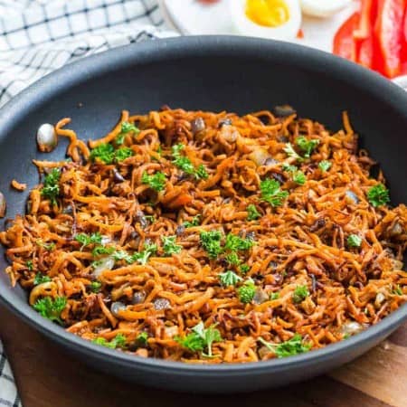 cooked sweet potato hash for weight watchers diet. Cast iron pan is on top of a wood triver with a blue and white dishtowel in the background.