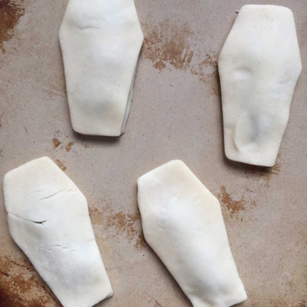 A cooking stone with four coffin shaped pieces of dough that will be made into pop tarts.