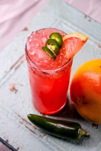 Image of jalapeno grapefruit margarita on counter. A jalapeno and grapefruit are next to image.