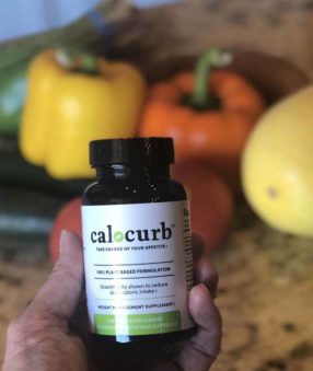 bottle of calocurb in front of healthy food