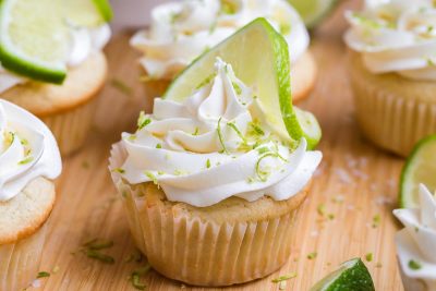 Margarita Cupcakes on a wooden board. The cupcakes are garnished with lime frosting and a sliced line.