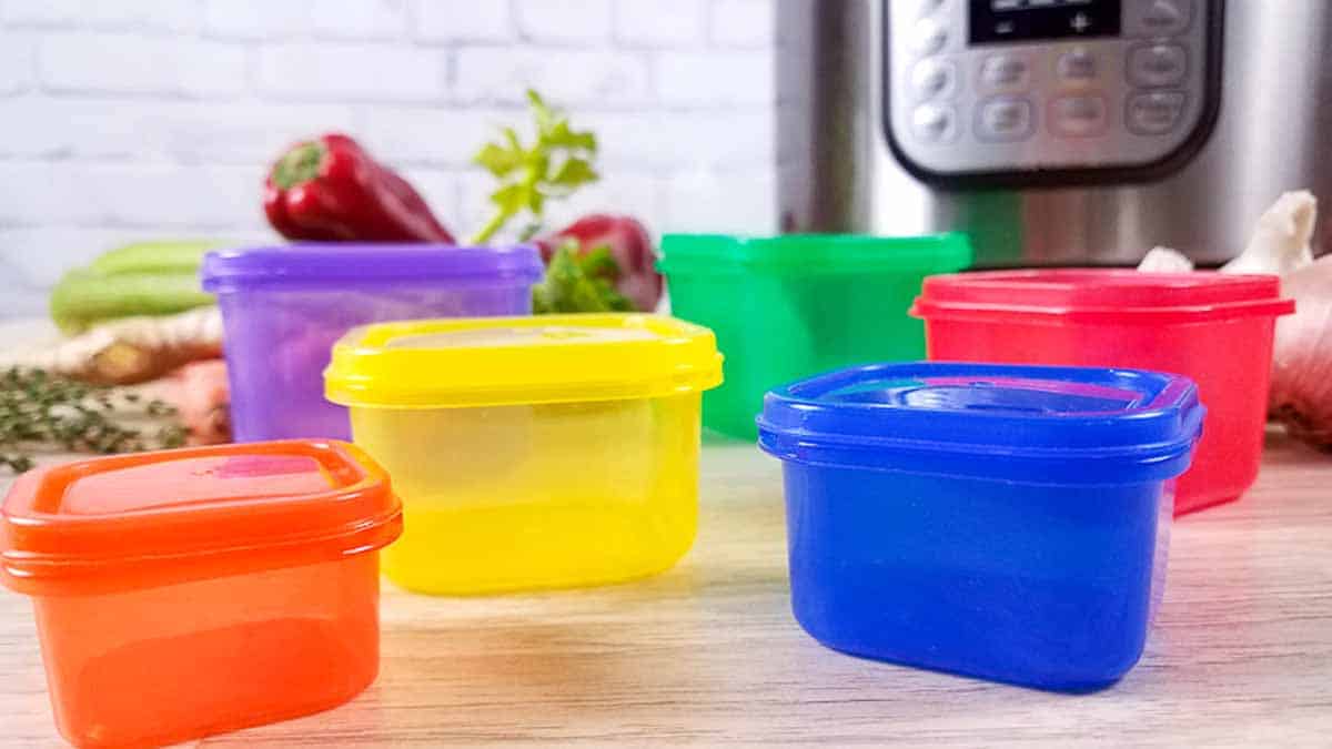 21 Day Fix containers on a wood countertop in front of an Instant Pot and raw vegetables.