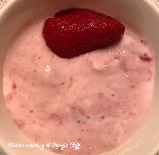 bowl of greek yogurt with chopped frozen strawberries mixed in