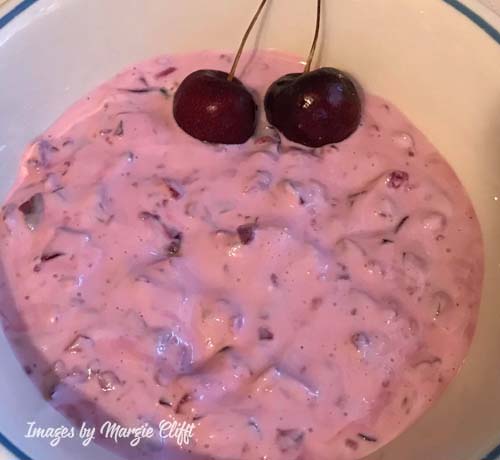 Greek yogurt with cherries cut up and mixed in, also two cherries on top