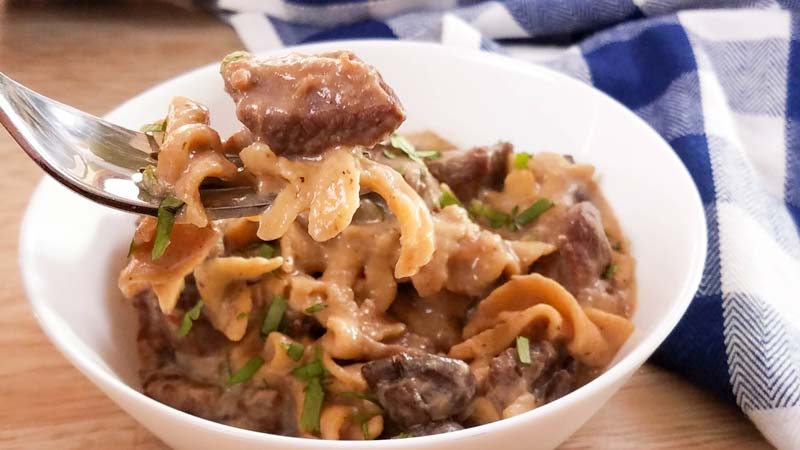 beef stroganoff in white bowl, some on fork