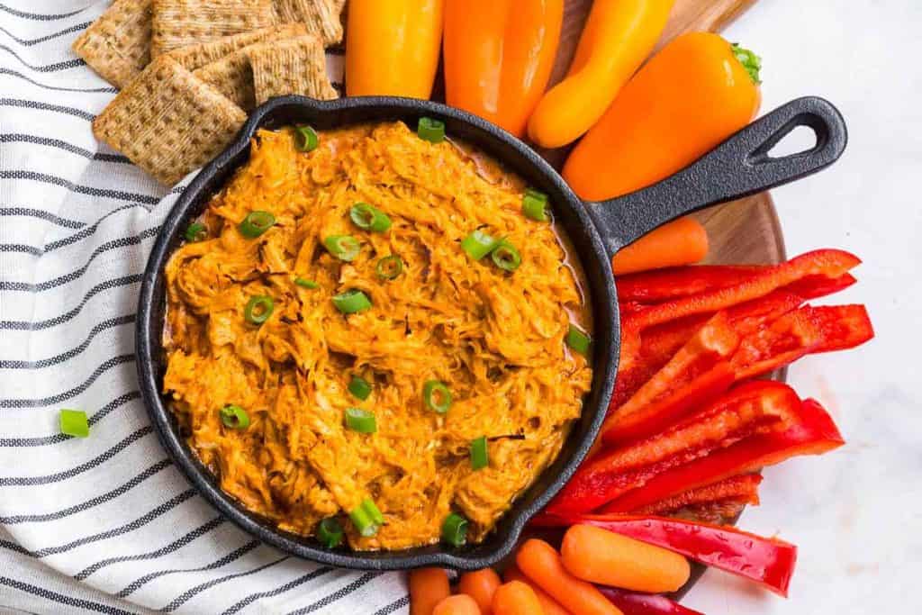 buffalo chicken dip in skillet surrounded by crackers and veggies