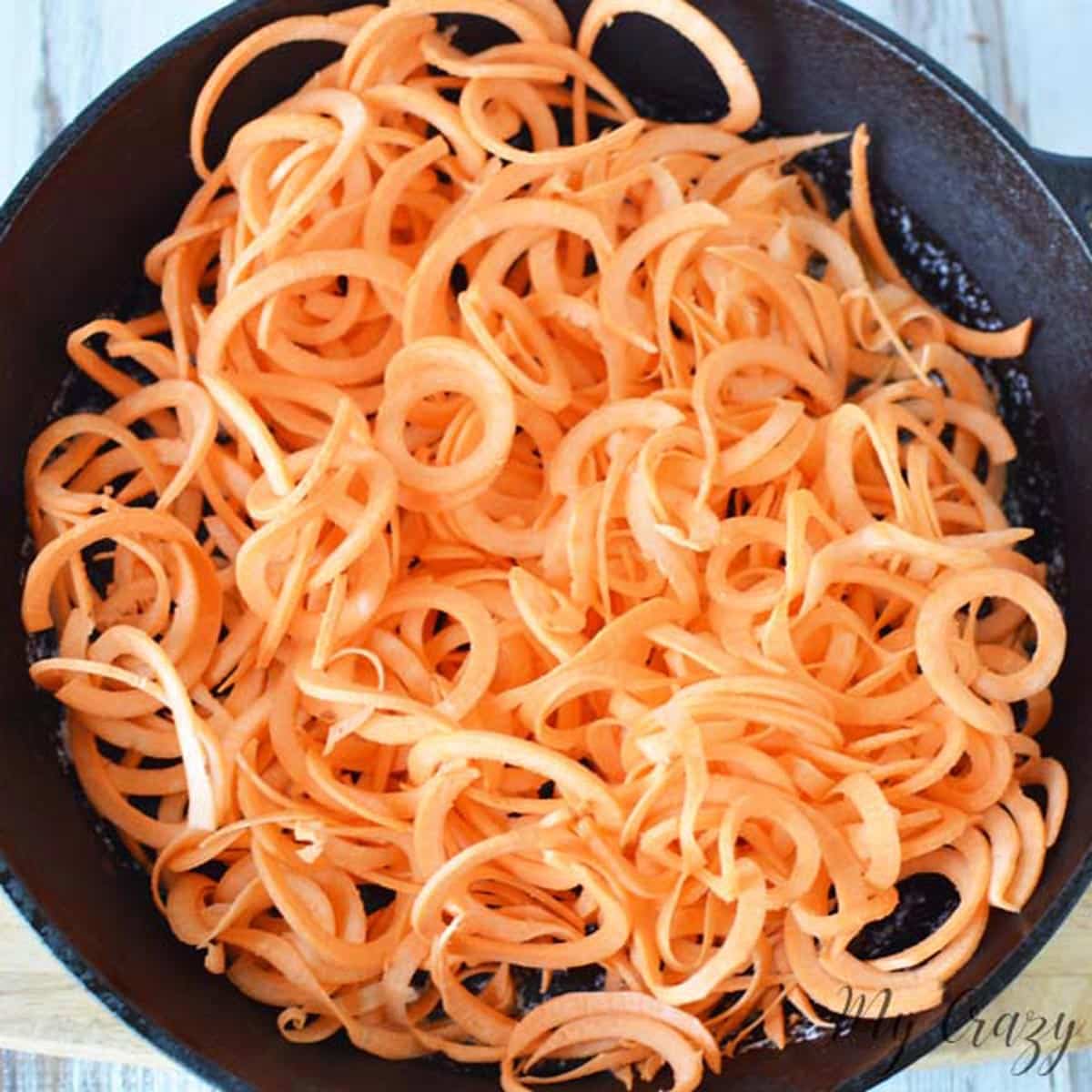 spiralized sweet potato noodles in a cast iron skillet.