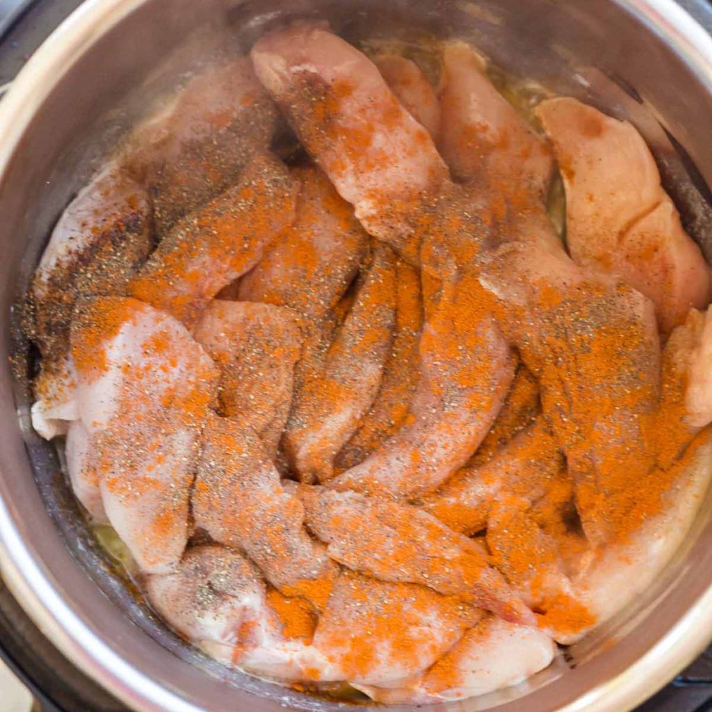 top down view of chicken, butter, and spices in an Instant Pot