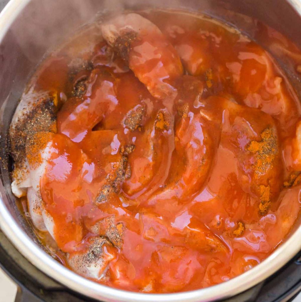 top down view of chicken and seasonings covered with hot sauce