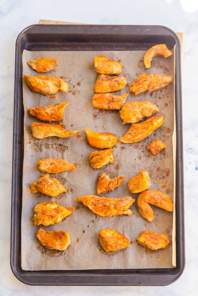 buffalo chicken bites on a pan with buffalo sauce
