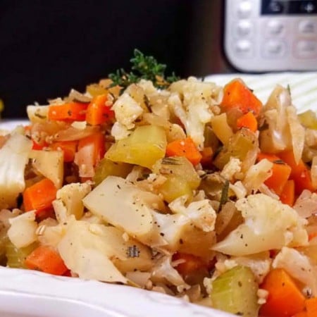 White plate with cooked cauliflower stuffing (cauliflower, carrots, celery, and onions) topped with spices.