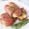 White plate with garlic rosemary potatoes. The plate is garnished with a sprig of rosemary.