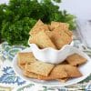 plate and bowl of healthy herb crackers with bunch of parsley behind.
