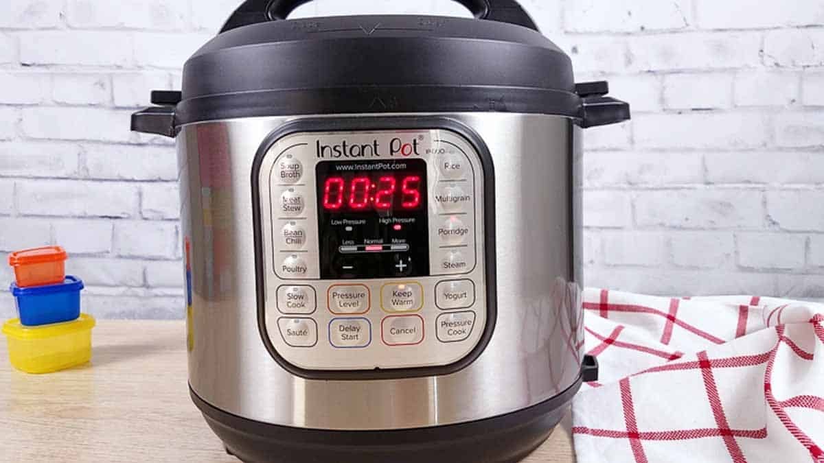 Closed Instant Pot set for cooking 25 minutes. Instant Pot is on a wood counter with a white brick background. 