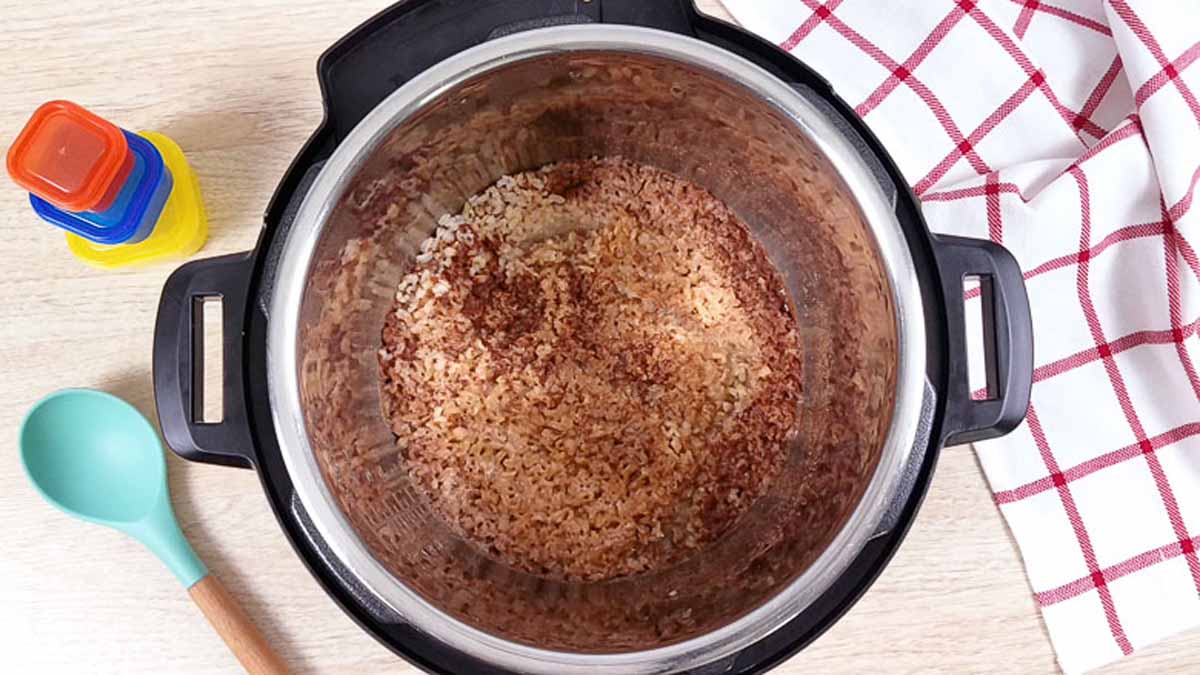 Open Instant Pot with cooked Rice Pudding inside. Spices are visible on top of the cooked rice pudding. 