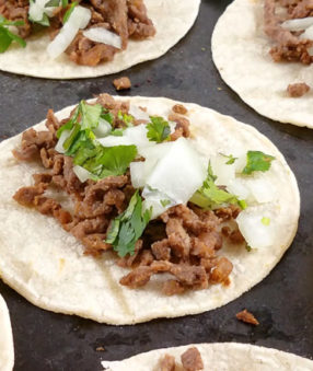 carne asada tacos on a black platter