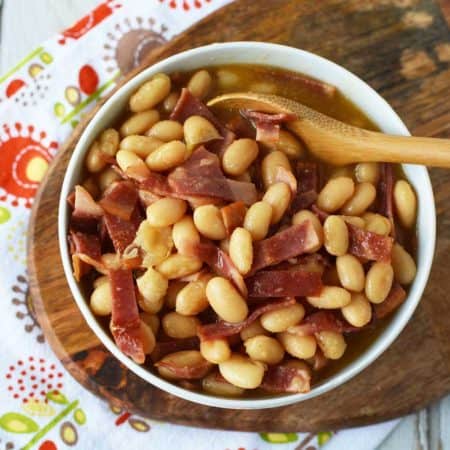 image from above of healthy pork and beans in a white bowl on top of a wooden board