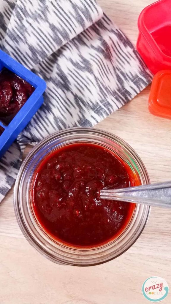 homemade enchilada sauce in a glass jar with a spoon inside.