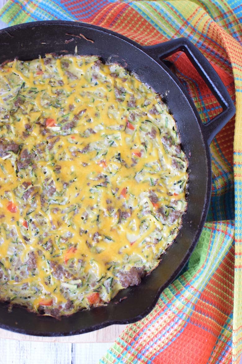 image of zucchini and sausage breakfast casserole in a skillet on a colored towel