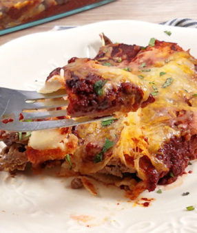 a white plate with healthy enchiladas-fork full of food