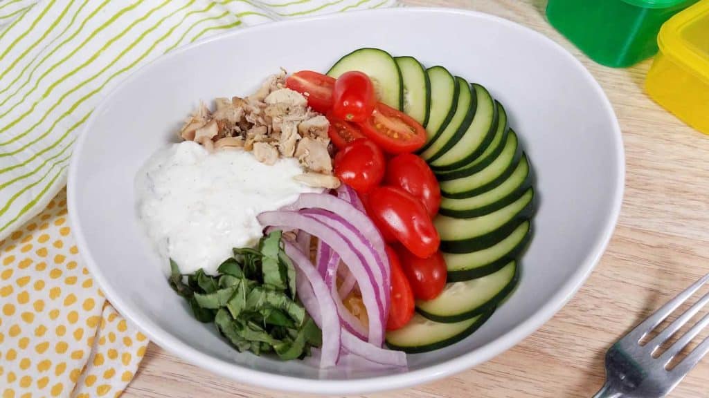 white bowl with cooked chicken gyro bowl, spaghetti squash, and fresh veggies