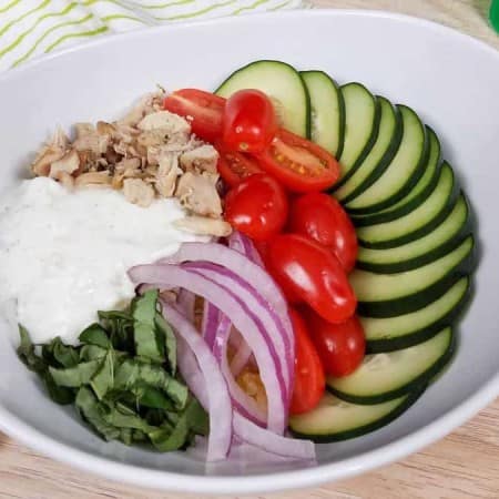 white bowl with cooked chicken gyro bowl, spaghetti squash, and fresh veggies