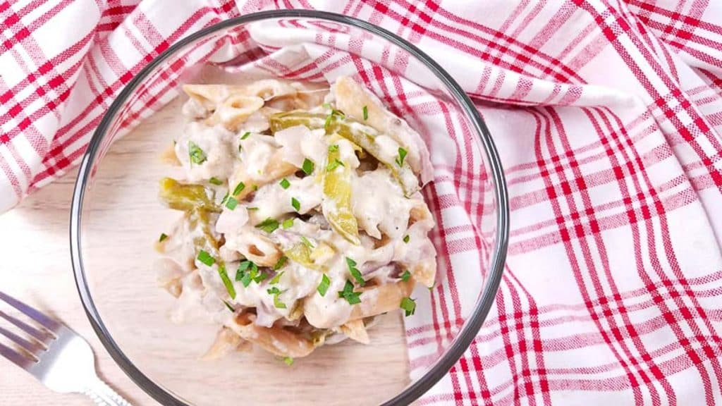 glass bowl of Healthy Chicken Philly Pasta with red and white checkered napkin and fork on wood table
