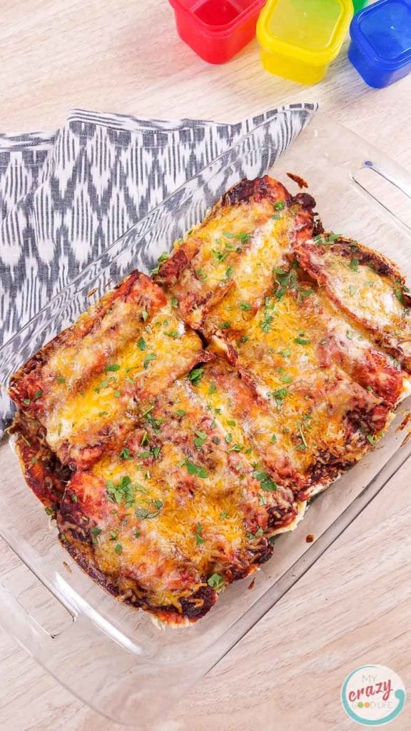 image of homemade beef enchiladas in a casserole dish on a gray and white towel