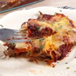 image without text of beef enchiladas on a white plate and on a raised fork
