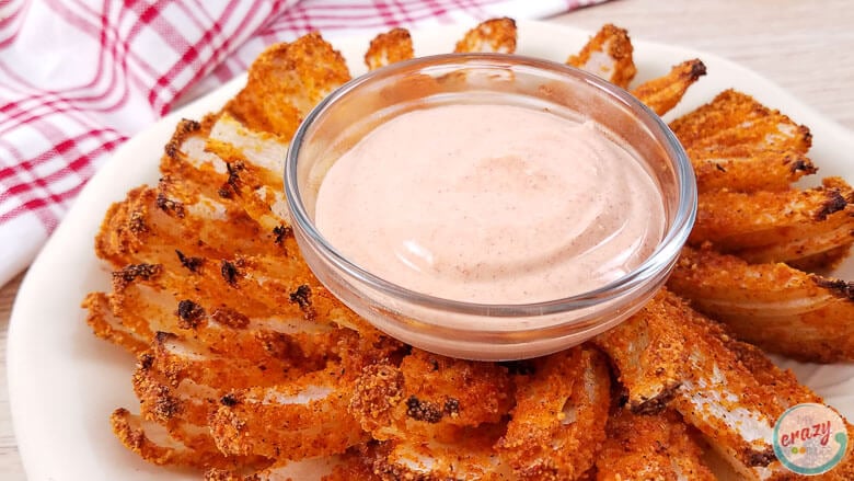 cooked onion with dipping sauce in center, on red and white napkin