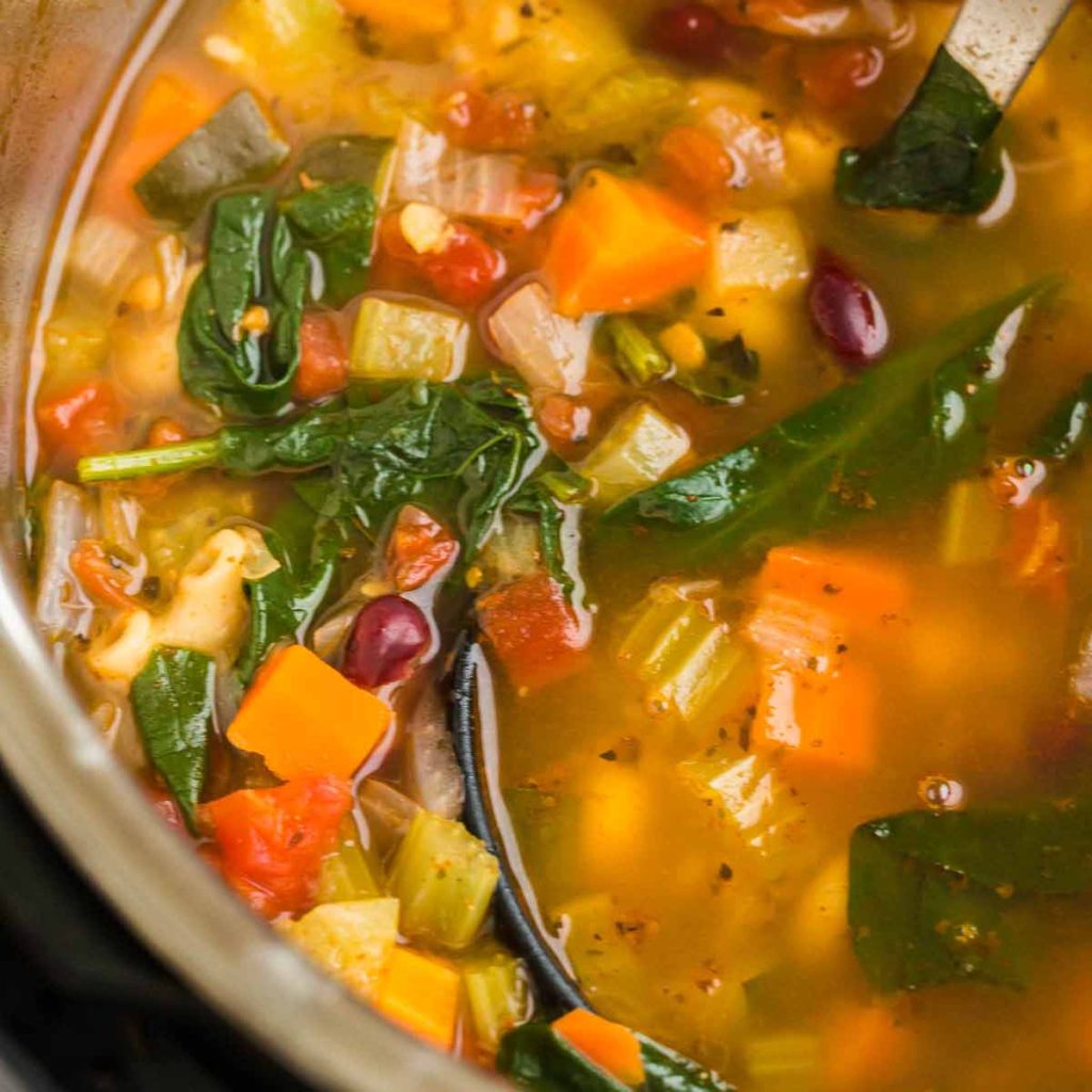 Instant Pot with cooked minestrone soup - you can see vegetables, pasta, and spinach on top.