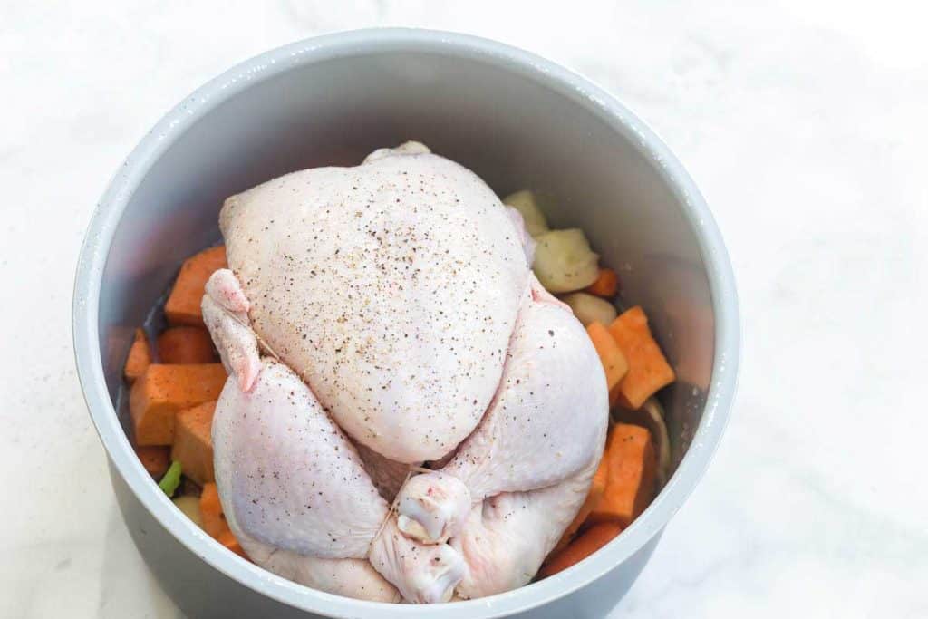 raw chicken on top of vegetables in a crockpot