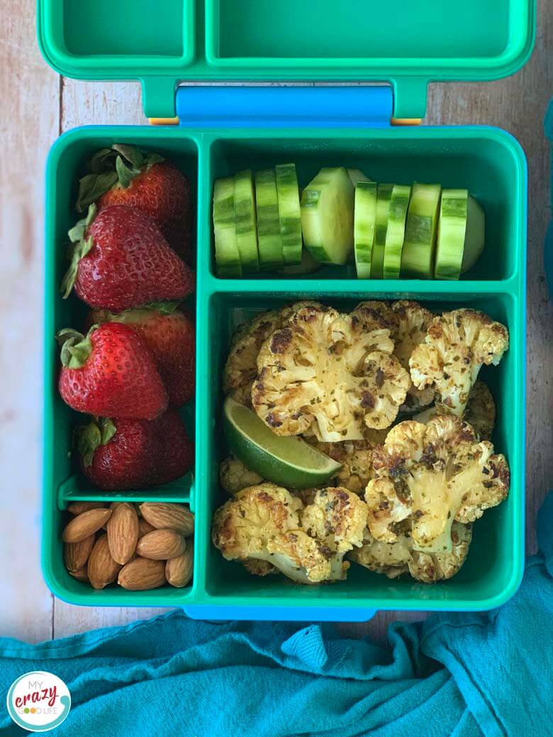 cauliflower steaks with chimichurri sauce in a bento box with fruits and veggies