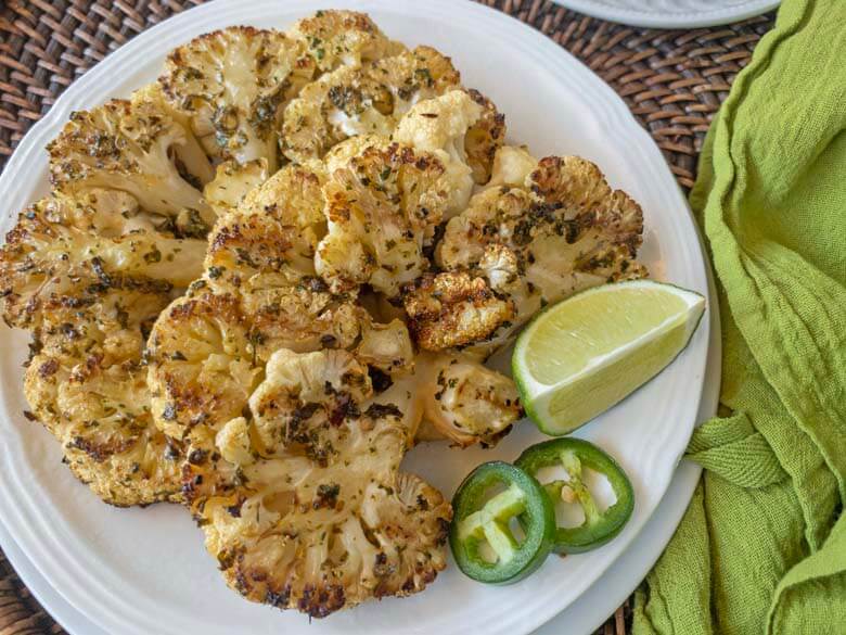 cauliflower steaks with lime and jalapeno on a white plate