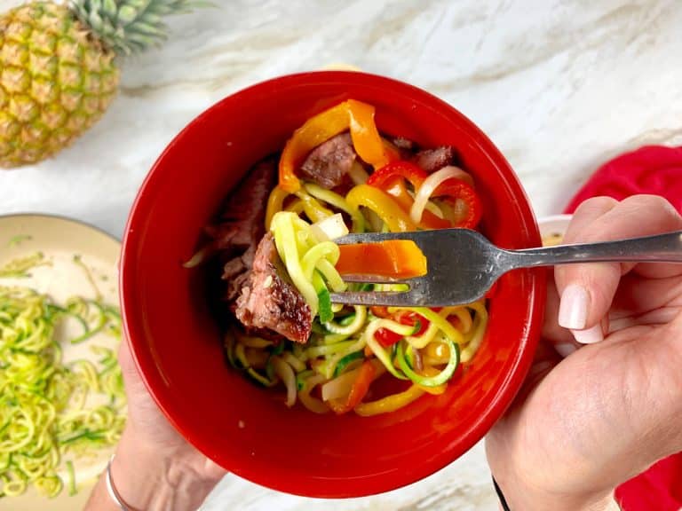 red bowl with zucchini noodles, steak and fajita veggies inside.