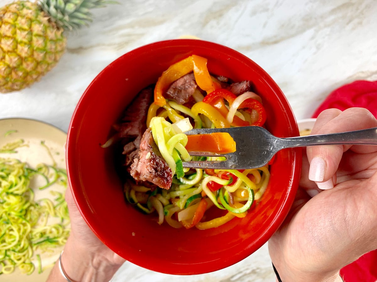 red bowl with zucchini noodles, steak and fajita veggies inside.