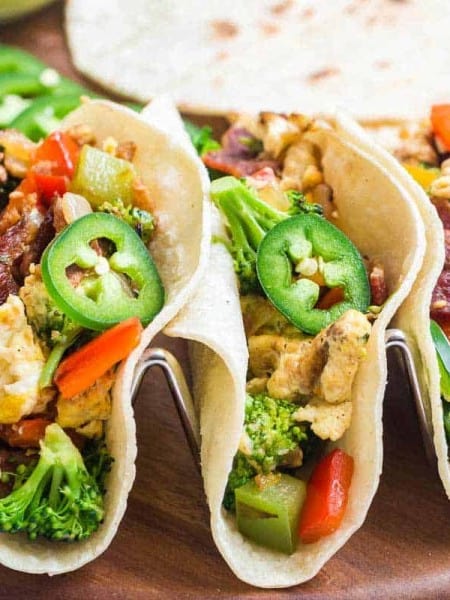 three breakfast tacos on a wood platter