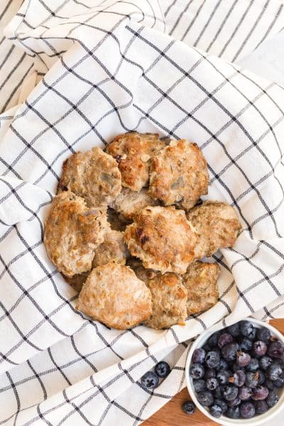 turkey sausage in bowl lined with cloth napkin. A small bowl of blueberries is below.