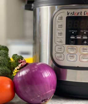 close up of instant pot with veggies off to the left