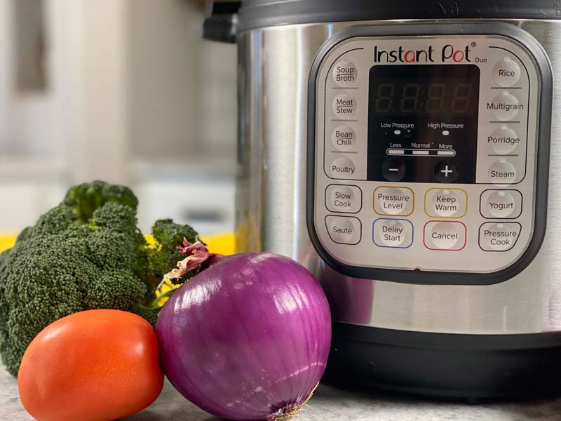 close up of instant pot with veggies off to the left