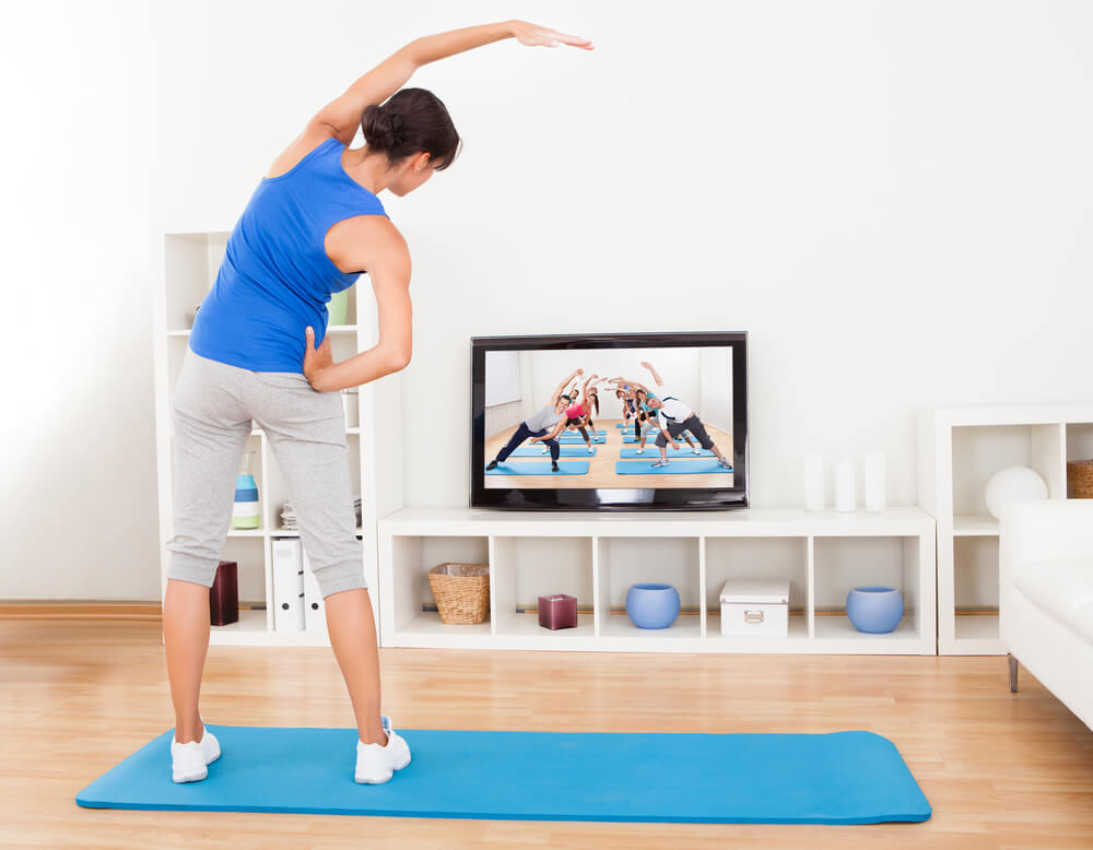 Woman watching workout on tv and exercising.