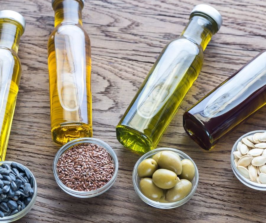 bottles of oils next to their ingredients laid out on a table.