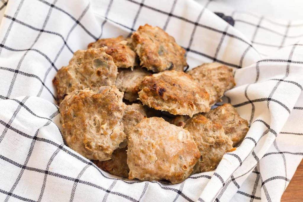 Image of homemade turkey sausage sitting on a white and black plaid cloth napkin.