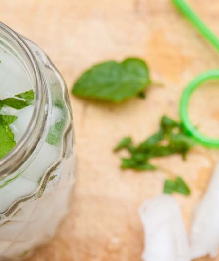 Stevia leaves in drink in clear glass with green straw on the side